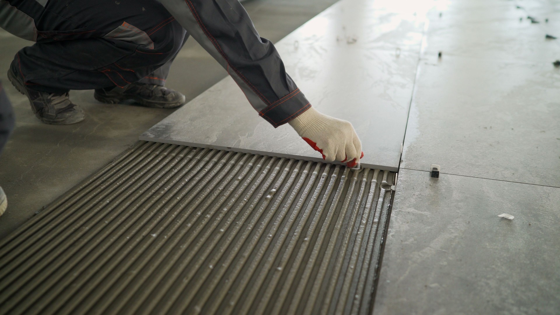 Installing a large ceramic tile. Workers lay large tiles on the floor